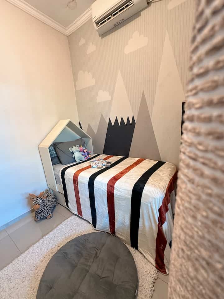 Beige and gray toned kids' room featuring a bed with toys and bookshelf, creating a cozy children's space