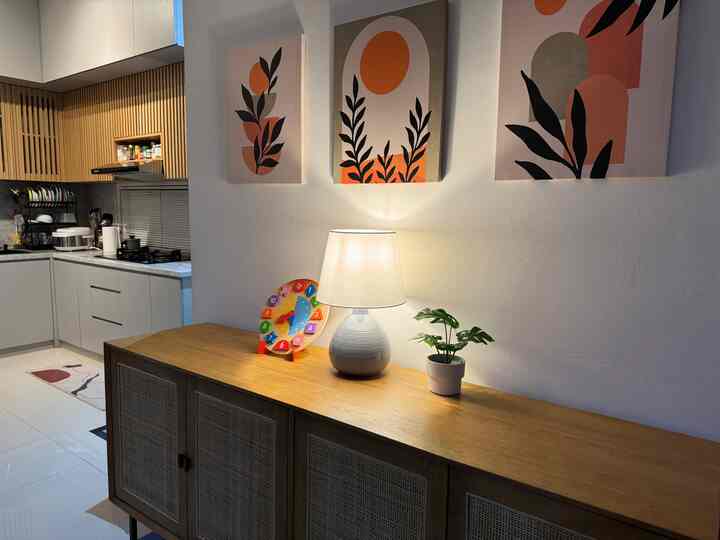 Natural color entrance space with wooden storage credenza, featuring a table lamp and indoor plant accent