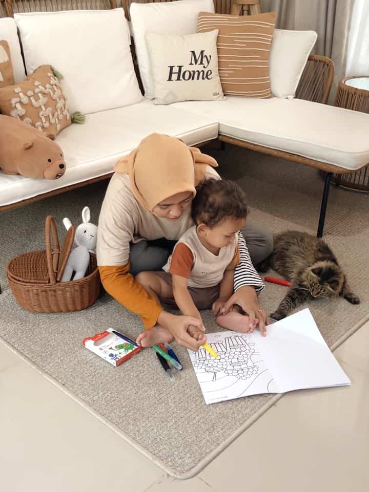 Natural-toned living room featuring a child, caregiver, and a cat in a family-centered setting