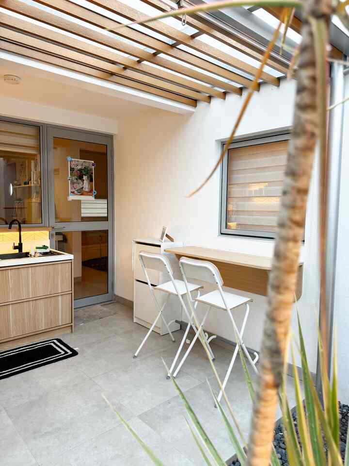 White and wood-tone kitchen space featuring foldable bar stools and a cabinet, compact and bright atmosphere