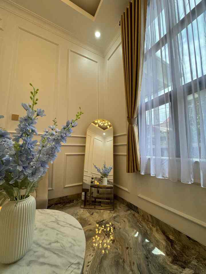 Living room corner in white and gold tones featuring a full-length mirror, curtains, and elegant marble floor