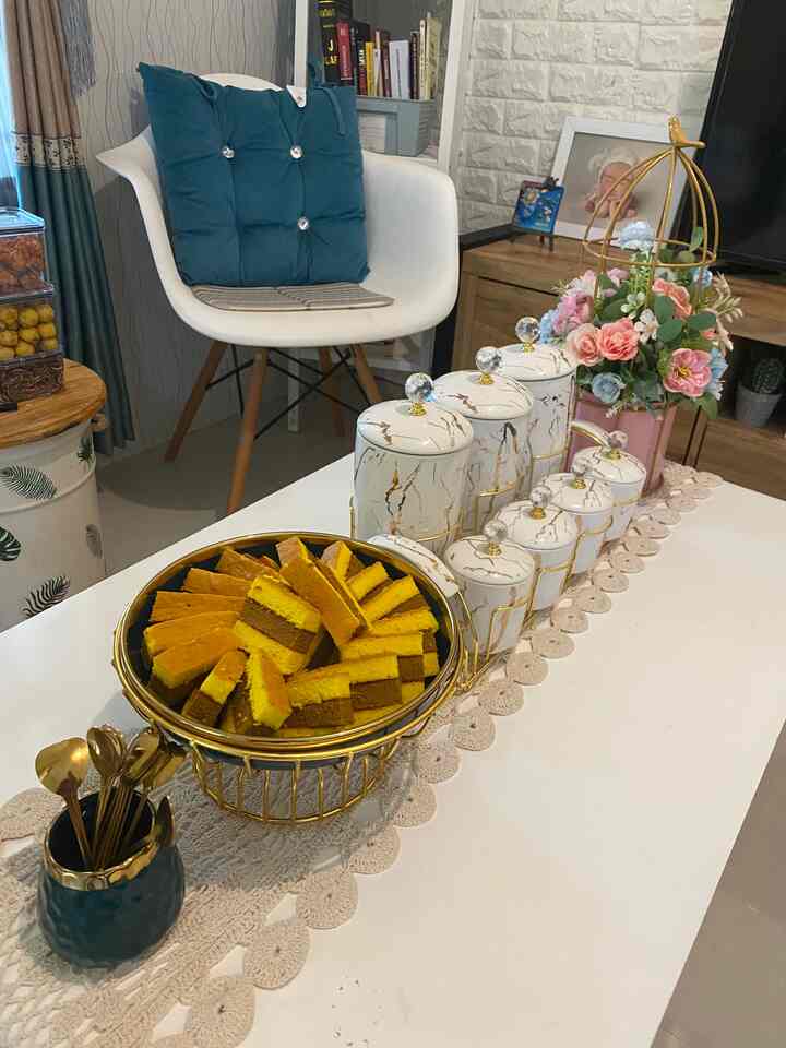 White and gold toned dining table featuring dining chair, ceramic canisters, and desserts in a cozy dining space