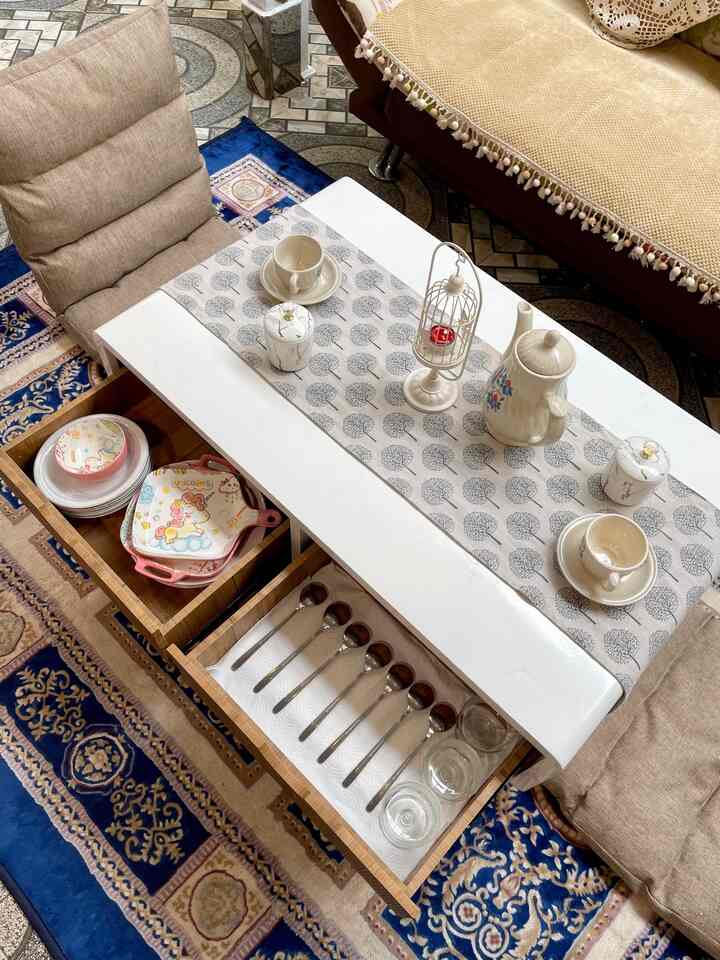 Beige cushioned chairs and wooden drawers with white coffee table create a cozy home cafe atmosphere in a living space