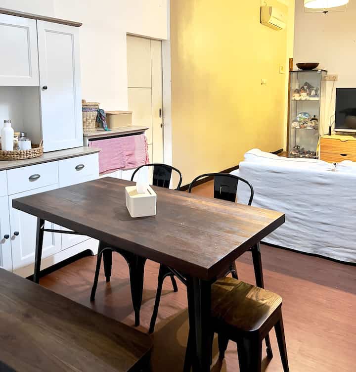 Wood tone and white living and dining room featuring wooden dining table and white sofa with a natural atmosphere