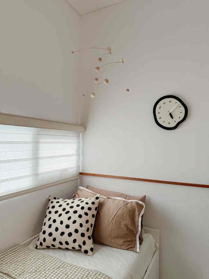 White and beige toned bedroom with patterned cushion and pillows, creating a calm atmosphere