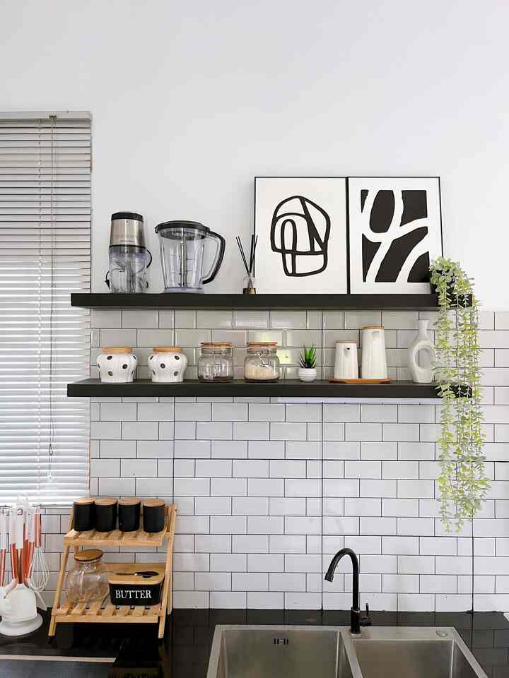 Modern kitchen space with white tiled walls, black shelves, and natural wood storage accessories arranged neatly