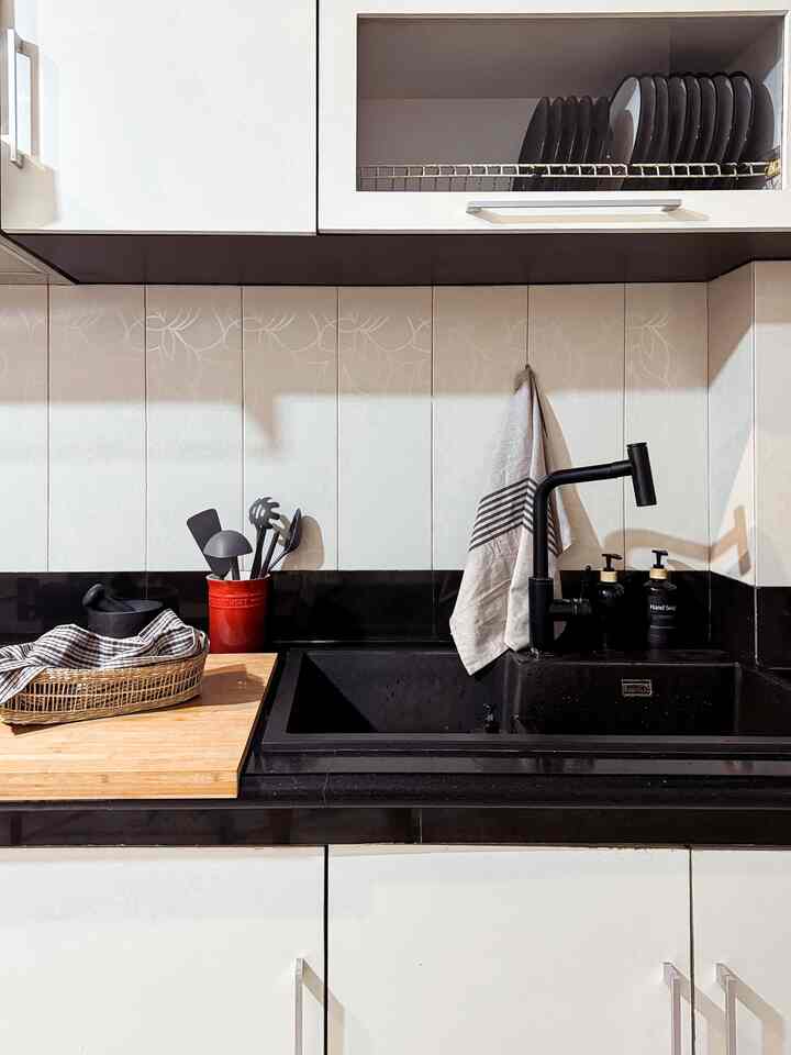 White and black toned kitchen featuring sink, cutting board, and kitchen utensils in a neat, organized interior
