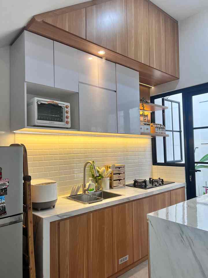 Hi... jangan bosan bosan ya lihat dapur segarisku. Meskipun mungil tapi tetap fungsional. Dalam menata dapur agar estetik namun tetap fungsional, aku memilih kitchen set bertema japandi dengan perpaduan warna kayu dan putih. Biar selaras aku juga menggunakan peralatan dapur dengan warna senada, seperti rice cooker putih-abu, oven putih-gold, dan wadah-wadah bumbu dengan warna natural kayu. Dengan begitu dapurku tetap fungsional namun estetik. Eitss jangan lupa tambahkan juga lighting, baik lighting utama dapur dan lighting led stripe karena sangat berfungsi menambah cahaya saat kita memasak terlebih masak saat malam hari atau pagi buta untuk menyiapkan bekal anak sekolah.

Tips: meja cor mirip top table mewah

Untuk meja kitchen set aku menggunakan meja cor yang didesain cor tipis agar seperti top table untuk menghemat budget. Jadi saat renovasi ketebalan meja di bagi 2, bagian atas dibikin lebih menjorok agar yg nampak bagian atas yang tipis. (Ketebalan cor 8-10cm, bagian atas 4-5 cm bawah 4-5cm dibuat lebih menjorok ke dalam). Menggunakan granit tile 60x120 motif marble dan backsplash ketamik putih motif bata. Dipadukan dengan HPL motif kayu, voilaaa menurutku ini cantik 😍 

#styingdapur
#MakeOverDapur
#RenovasiDapur
#dapurJapandi
#kitchendesign
#DesainDapur
#DapurMinimalis
#DapurBawahTangga