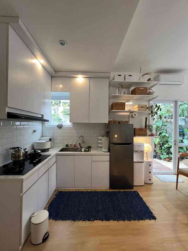 A bright Scandinavian style kitchen featuring white and wood tones, large windows, and open shelving creating a natural and airy atmosphere