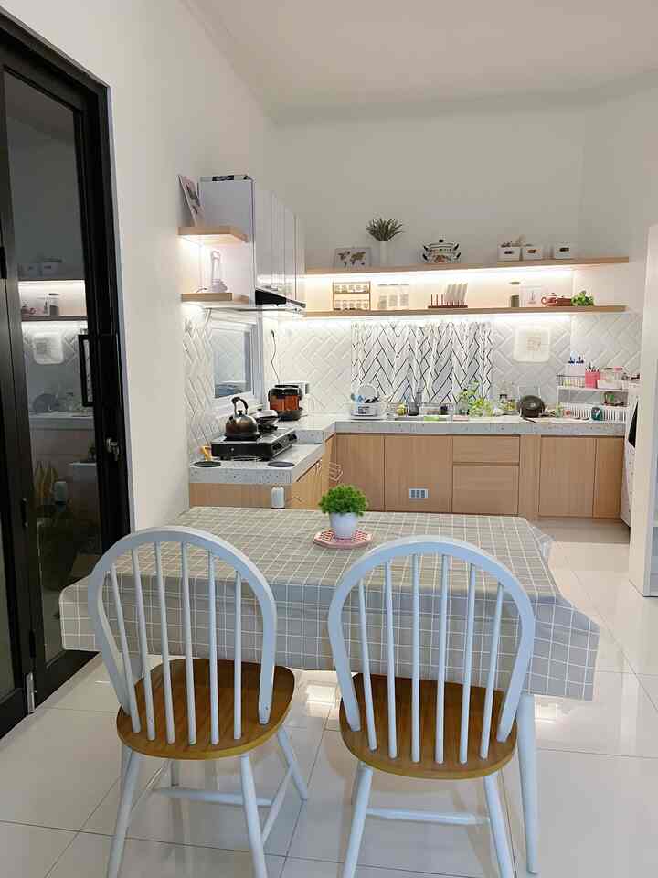 White and wood tone kitchen featuring long shelves and dining table, creating a clean and modern interior