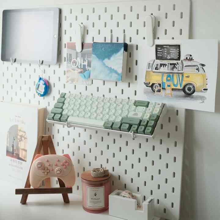 White SKÅDIS pegboard holding a keyboard and small items in a minimalistic home office setup