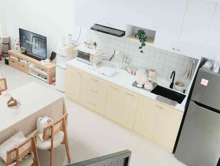 White and wood tone kitchen featuring kitchen set, dining table, and plant in a simple natural modern space