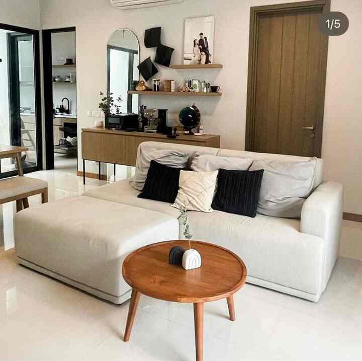 White and brown toned living room featuring sofa and round wooden coffee table with a modern atmosphere