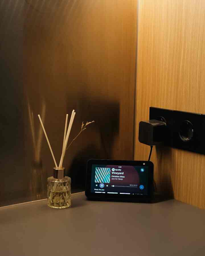Modern space with warm wood tone wall and minimal table holding a diffuser and Alexa Echo Show 5 smart device