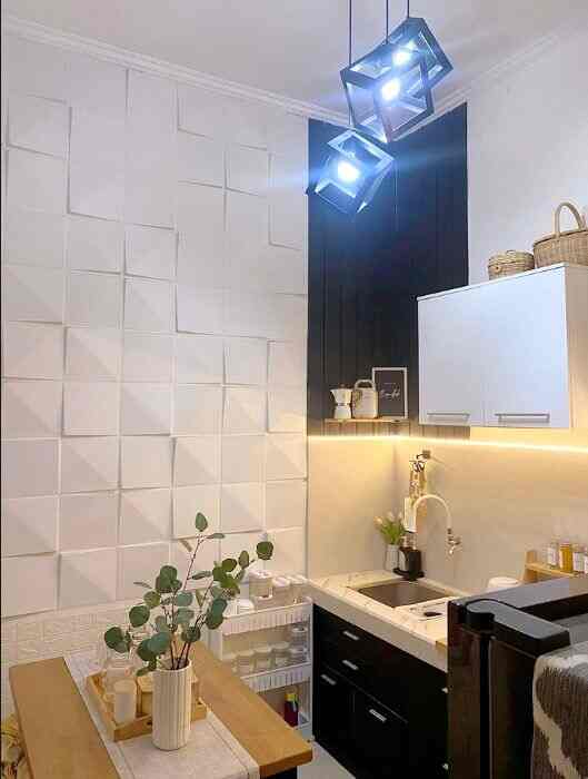 A compact kitchen space in white and black with wood tones, featuring pendant lights and decorated shelves for a modern look