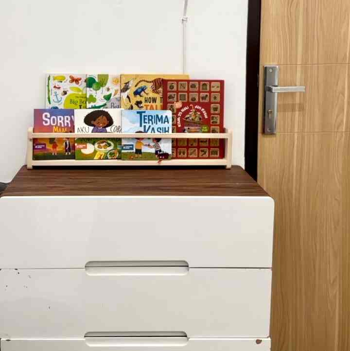 White and wood tone kids' room featuring a bookshelf with children's books and practical storage