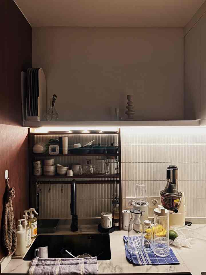 White and wood-tone kitchen featuring a sink, transparent glass jars, and ambient LED lighting creating a cozy atmosphere