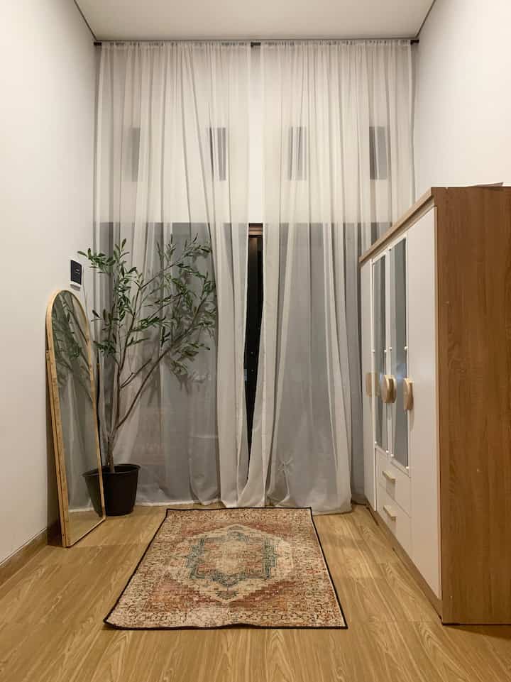 Minimalistic room with natural wood tones featuring balcony access, closet, and full-length mirror creating a cozy interior