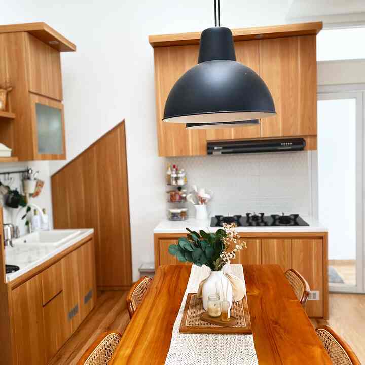 Wood tone and black kitchen and dining area featuring a pendant light and cooktop, creating a cozy and harmonious atmosphere