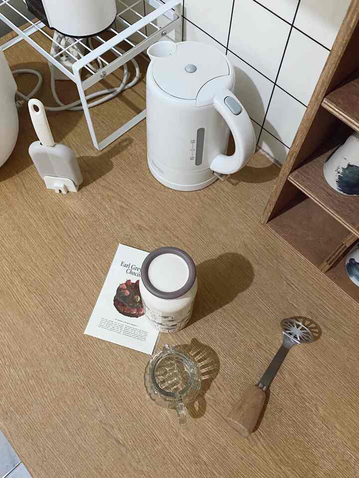 Natural wood tone kitchen countertop featuring an electric kettle and kitchen utensils with clean and cozy atmosphere