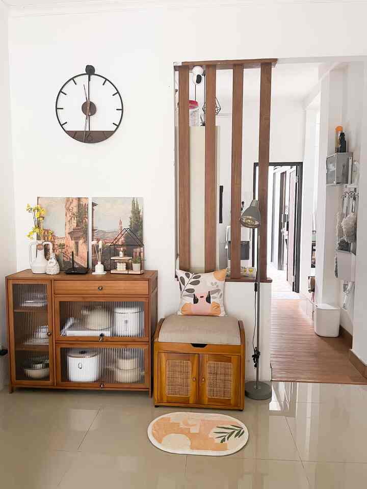 Entrance living space featuring wood tone furniture, white walls, wall clock, and floor lamp with cozy atmosphere