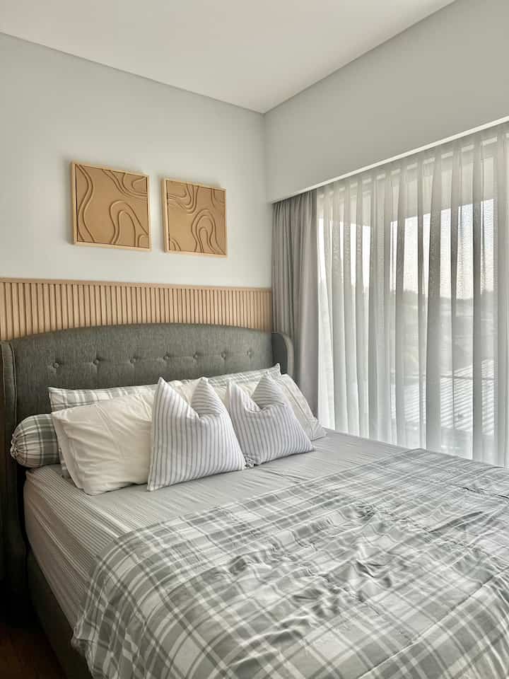 White and gray toned bedroom featuring natural wood wall panel and simple bedding creating a cozy atmosphere
