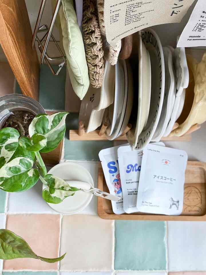 Pastel-toned kitchen tiles floor with plate rack and plant, featuring a natural color kitchen space