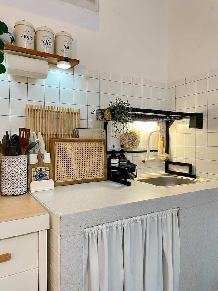 A white and wood tone kitchen space featuring a sink, storage ideas, and neat utensils with a clean and simple atmosphere
