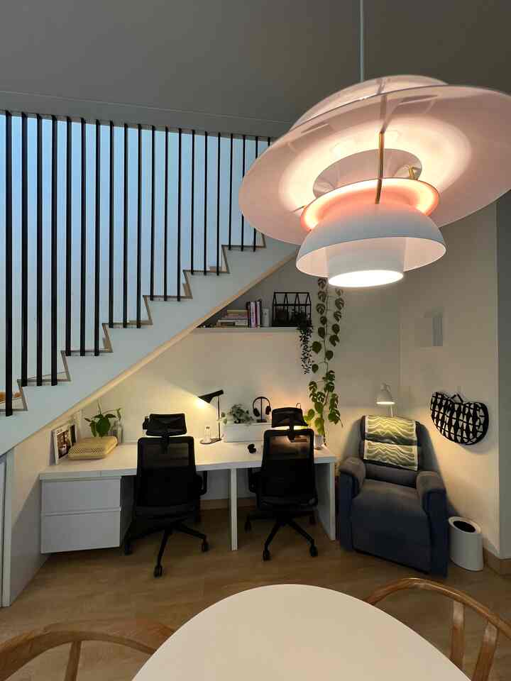 Minimal natural modern home office space with white and wood tones, featuring pendant lighting and a cozy armchair in a living room style