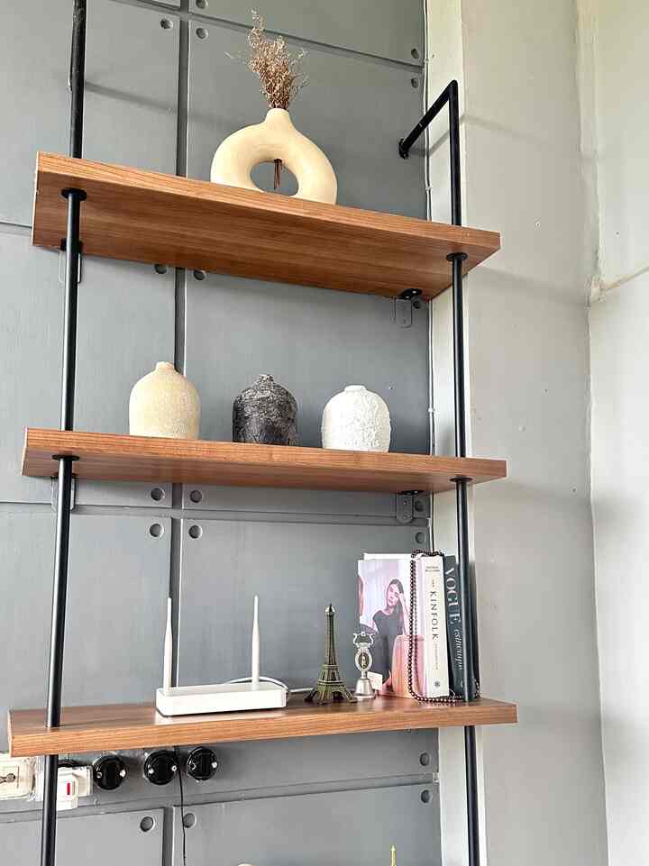 Industrial style space with gray metal wall and wooden shelves featuring various vases, books, and decorative objects