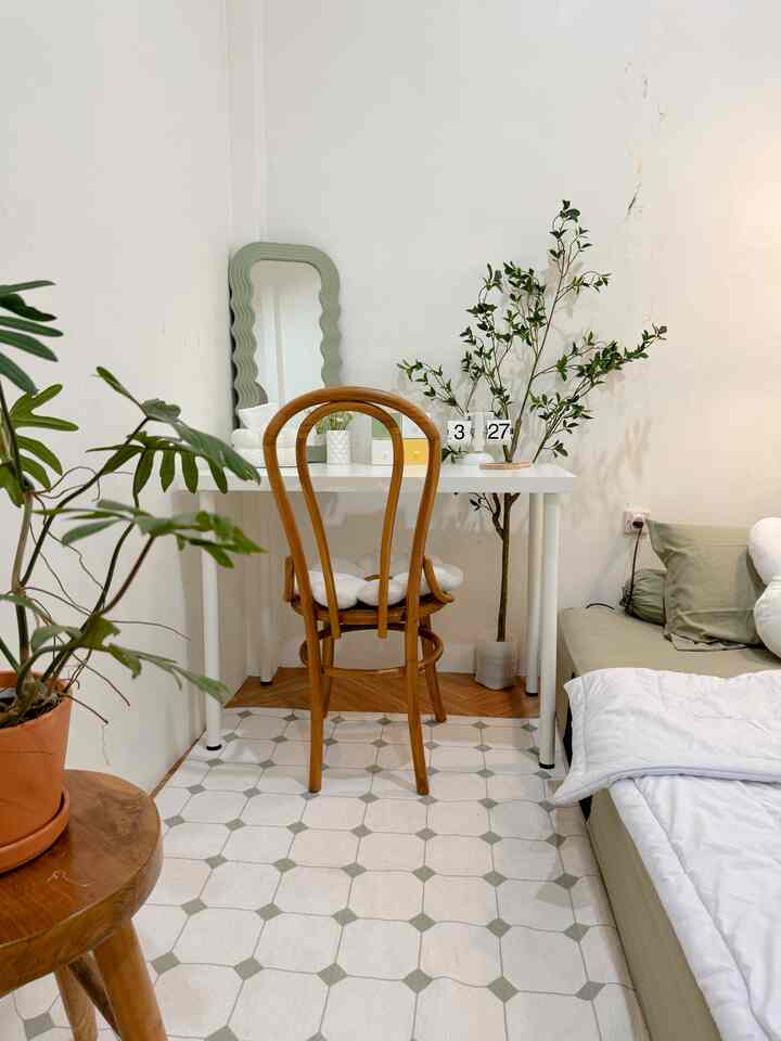 Natural toned small studio apartment featuring a sofa bed and wooden chair with a warm atmosphere