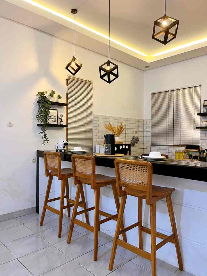 Kitchen space featuring white walls, wooden bar stools, blinds, with warm LED strip lighting and cube pendant lamps creating a cozy atmosphere