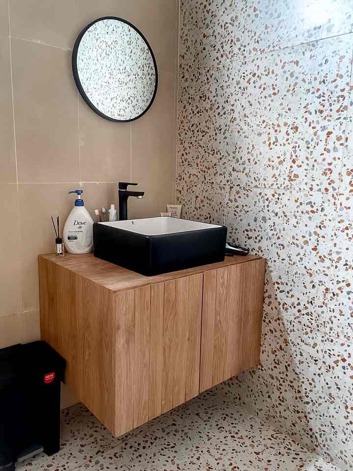 Beige and wood tone bathroom featuring a ceramic sink and round mirror in a clean, modern space