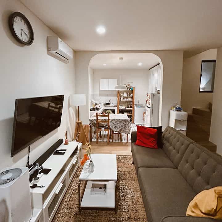 White and brown tone living and dining room featuring sofa and dining table in cozy compact space