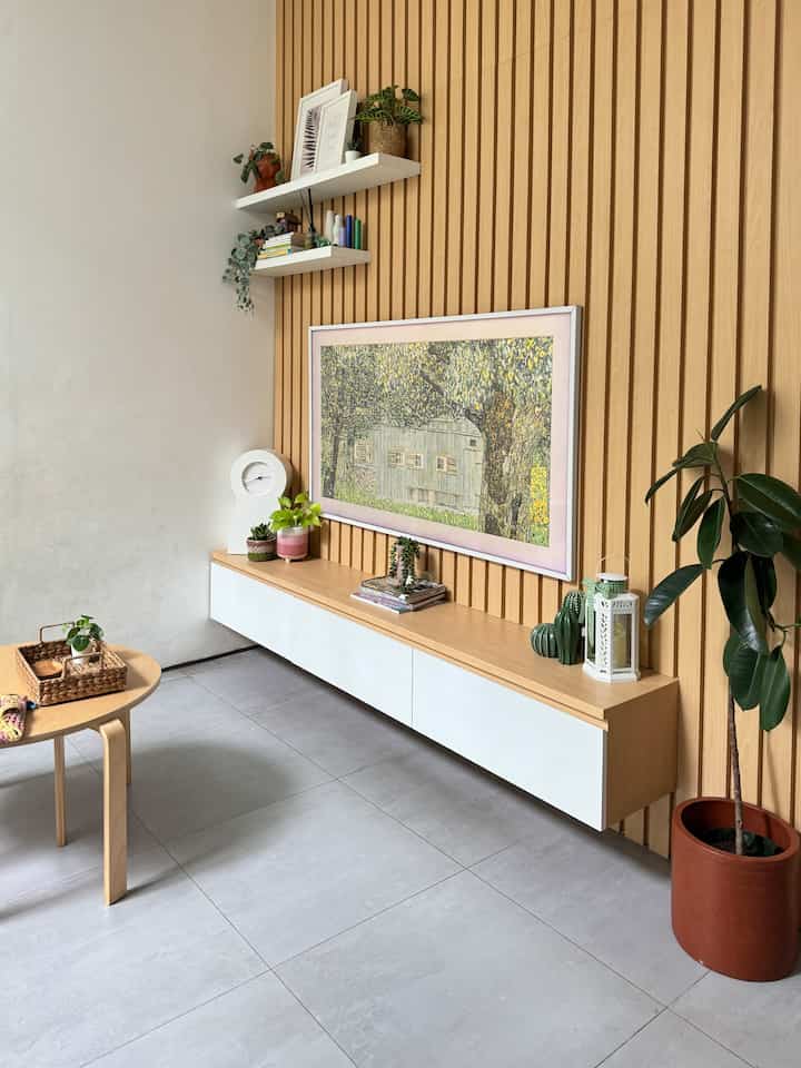 Natural wood tone and white living room featuring wall art, plants, and a floating TV stand with a warm, simple atmosphere