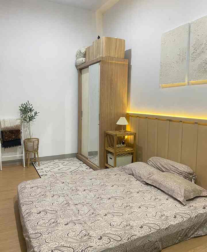 Beige and natural color bedroom featuring patterned bedspread and wood-toned wardrobe creating a cozy atmosphere