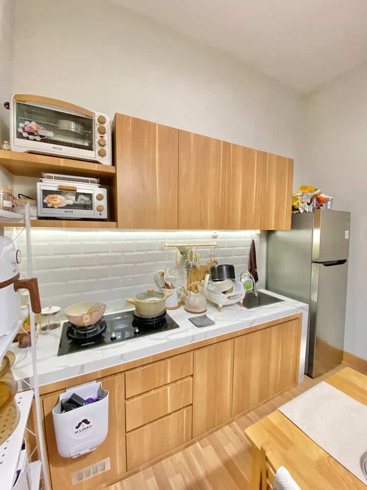 A small kitchen and dining area with white walls and wood-toned furniture, creating a neat and cozy atmosphere