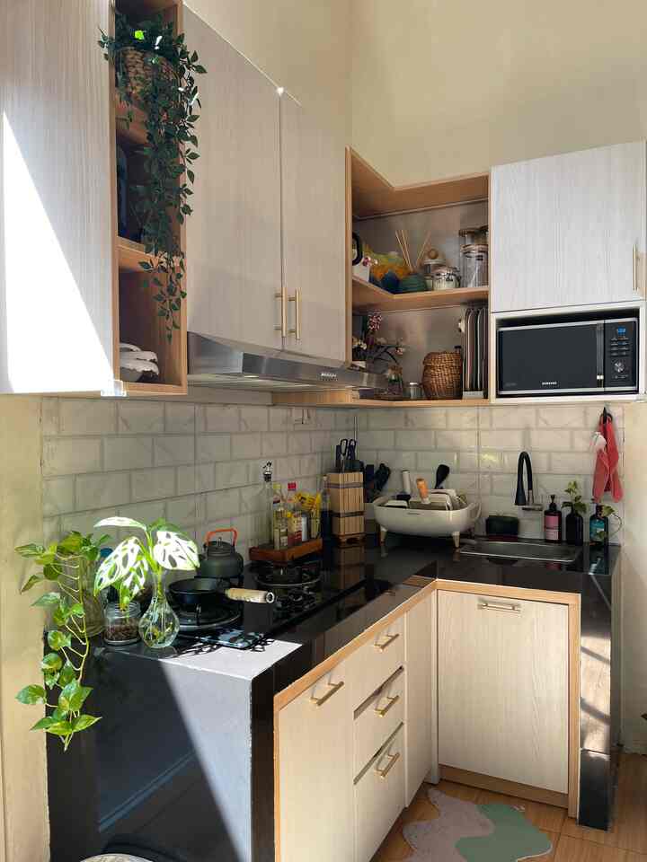 Bright kitchen space in white and black tones featuring upper cabinets, plants, and organized modern style