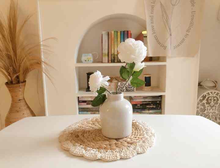 Warm beige and white toned dining room featuring a central vase with flowers on a round placemat, creating a clean and natural atmosphere