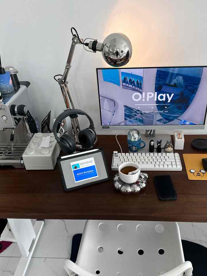 Compact home office with white walls and brown desk featuring a monitor and gaming keyboard for remote work setup