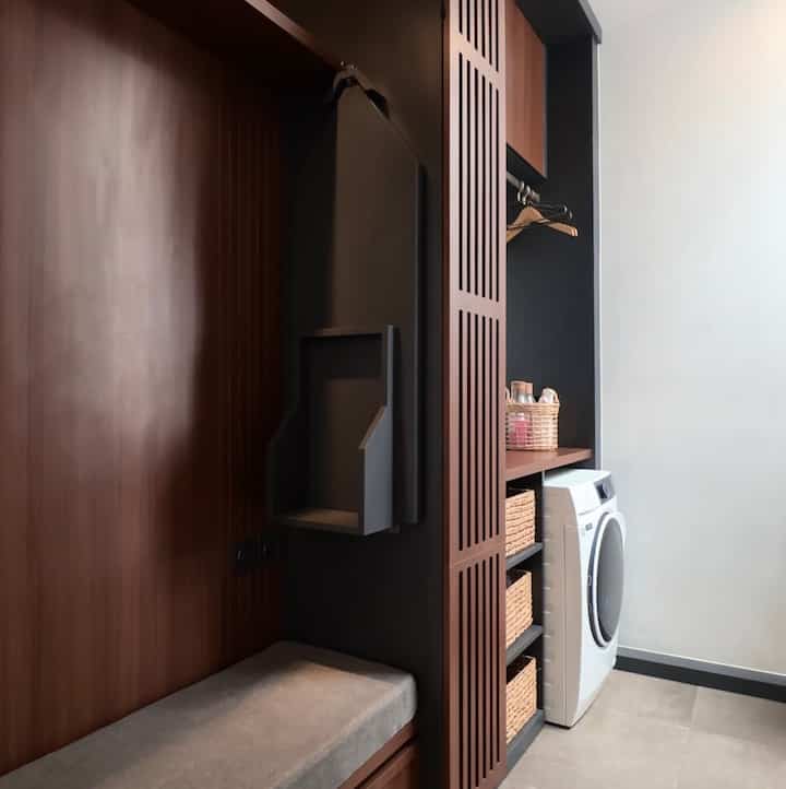 Laundry entrance space featuring brown wood tones and white walls, neat arrangement of storage cabinets and washing machine