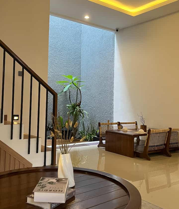 A white and natural color dining room featuring wooden table and chairs with indoor plants creating a cozy atmosphere