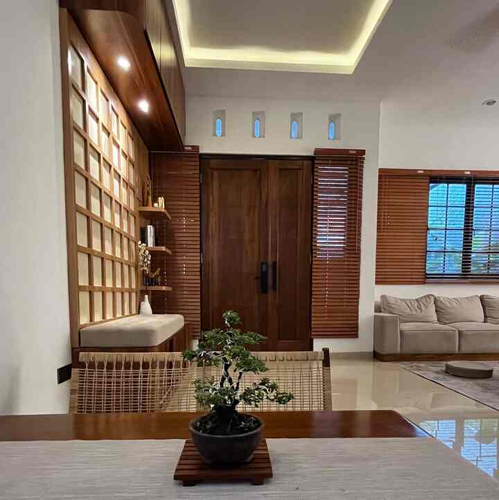 Wood tone and beige living room featuring sofa, rattan chair, and bonsai plant in a natural and cozy Japandi-style interior