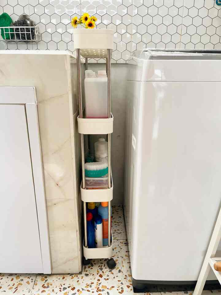 White and beige narrow laundry space featuring a slim gap storage rack neatly holding cleaning supplies