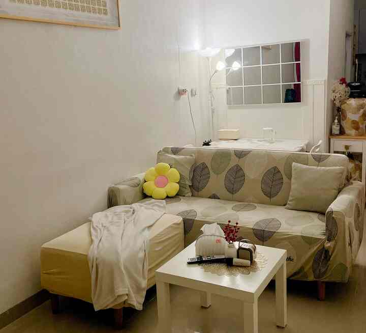 White-toned living room featuring a leaf-pattern sofa, coffee table, and floor lamp with a simple, natural atmosphere