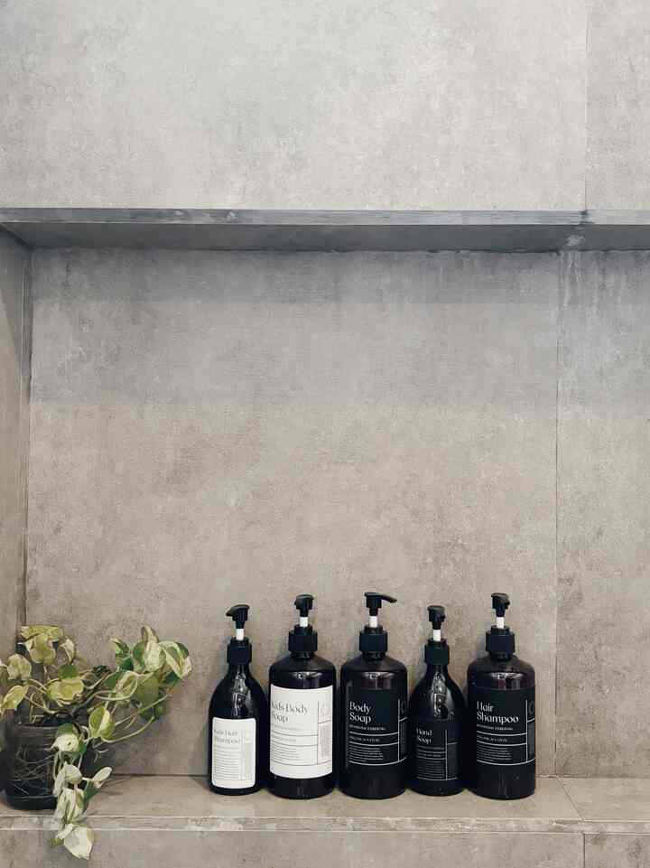 Natural tone bathroom shelf featuring diffuser bottles and a plant with a clean minimalist atmosphere