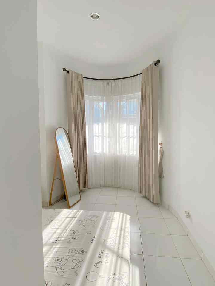 White and wood tone bedroom featuring a full-length mirror and bright curtains, creating a clean and spacious feel