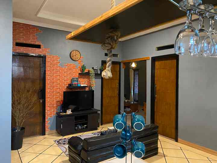 Wood tone and gray walls frame a living room with black sofa, TV stand, and brick-patterned wallpaper accent
