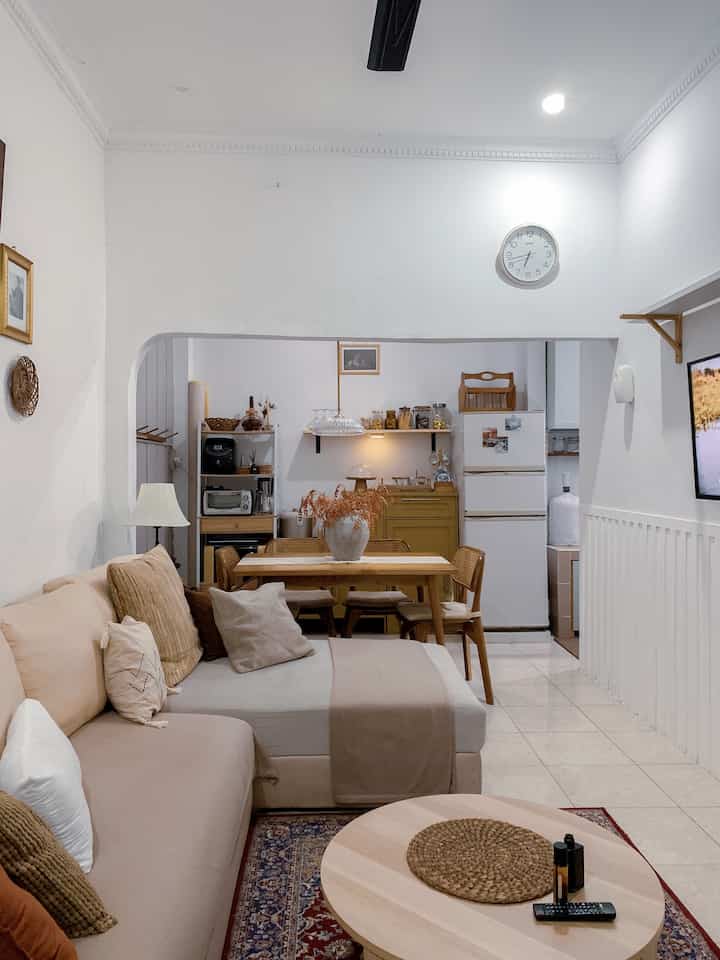 White and brown toned living and dining room featuring wooden furniture and a cozy sofa in a natural Japandi style space