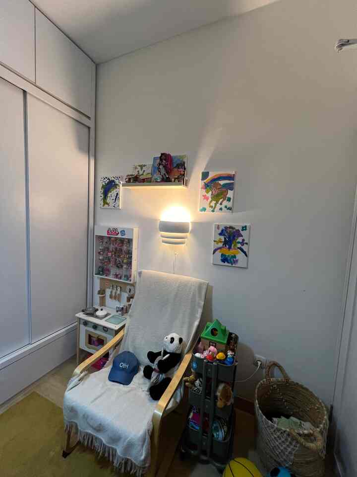 A cozy kids' room with white walls and wood-tone furniture, featuring children's toys and colorful wall art